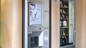 Un distributeur automatique de collations et une machine à café, avec une enseigne indiquant un hôtel proposant des chambres et le petit-déjeuner au-dessus.