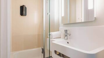 A modern bathroom with a glass shower enclosure, a white sink, and a mirror above it.