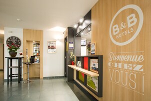 Un espace d’accueil avec un comptoir de réception en bois, une horloge et un panneau d’accueil.
