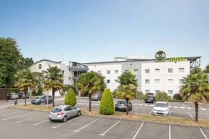 Un hôtel-restaurant de type « bed and breakfast » au design moderne, doté d’un parking pouvant accueillir plusieurs voitures et agrémenté de palmiers.