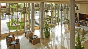 Un hall d’entrée spacieux avec une façade en verre, un mobilier moderne et des plantes d’intérieur.