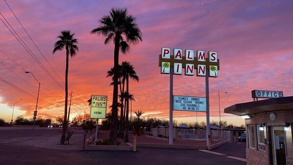 A motel sign with "PALMS INN" and a sign for "FAMILY OWN'S NICE CLEAN 220 CHANNELS 40 IN HD TV".