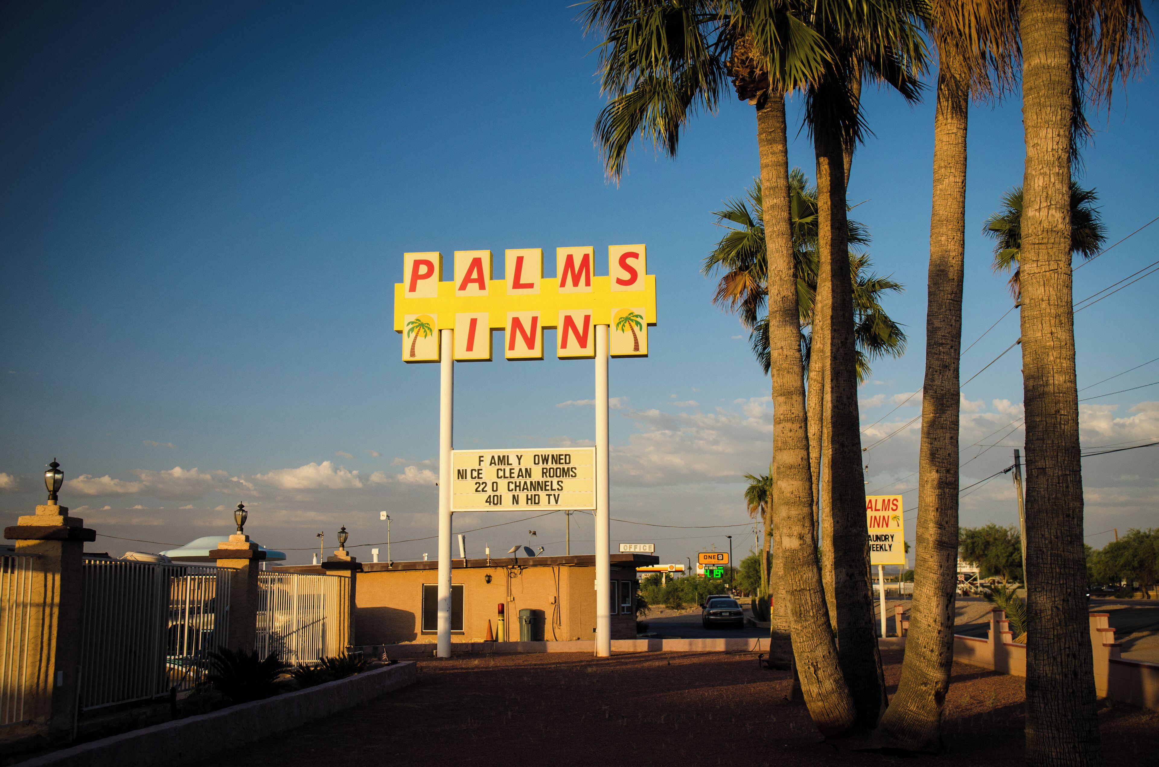 Placa indicando 'Palms Inn' com detalhes sobre comodidades, incluindo propriedade familiar, quartos limpos, 22 canais e TV HD 401N.