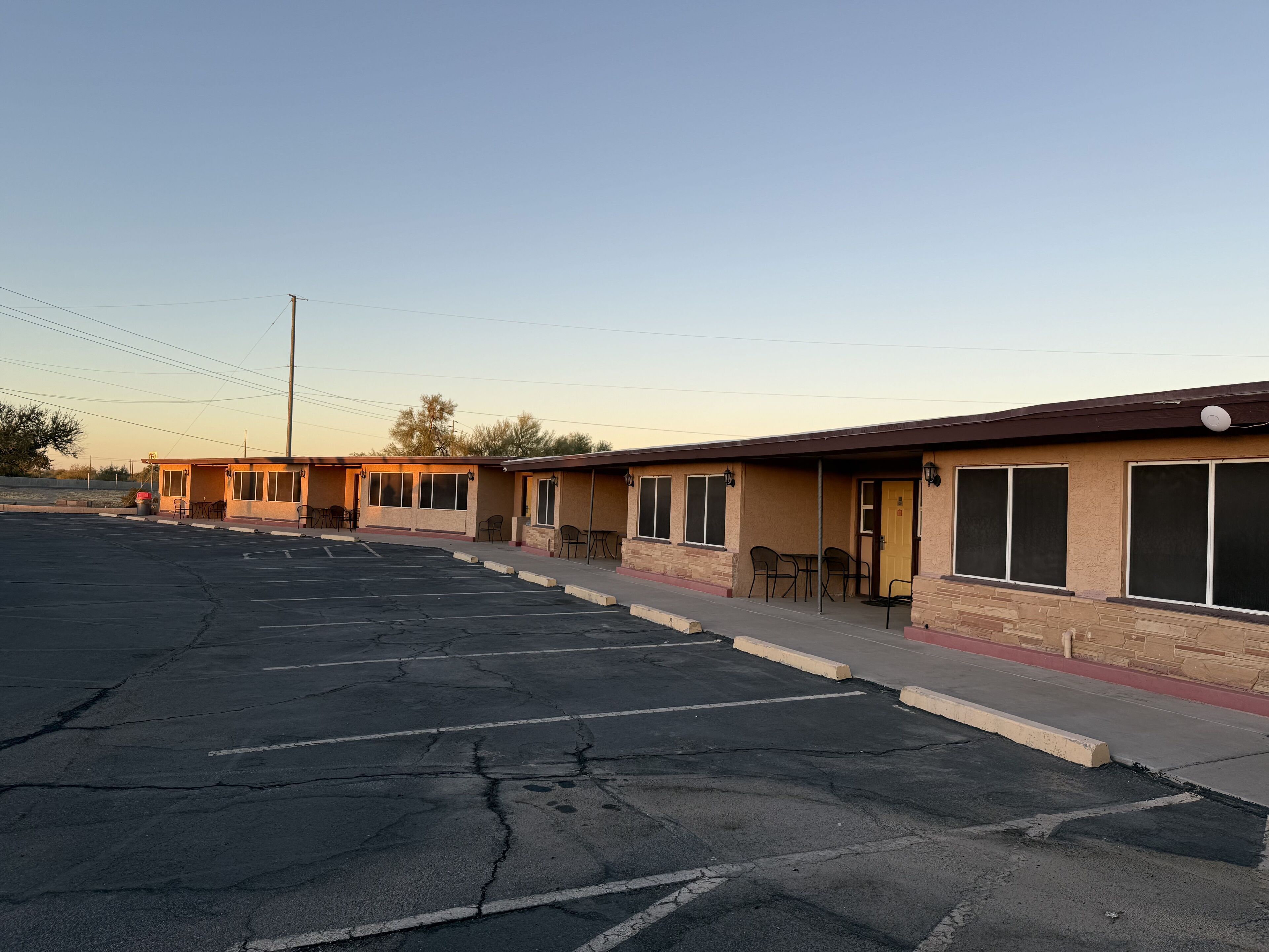 Filas de habitaciones de motel con entradas individuales, zonas de estar exteriores y un estacionamiento.