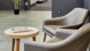 Een moderne wachtruimte met een leren fauteuil, een klein houten tafeltje met een tijdschrift en een bloempot.