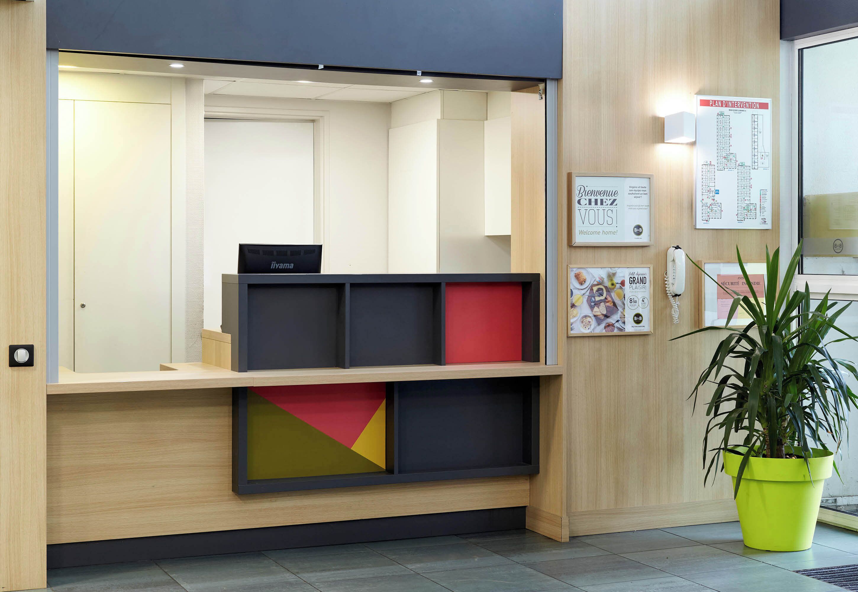 Een receptiebalie van hout, een kamerplant en een kaart aan de muur.