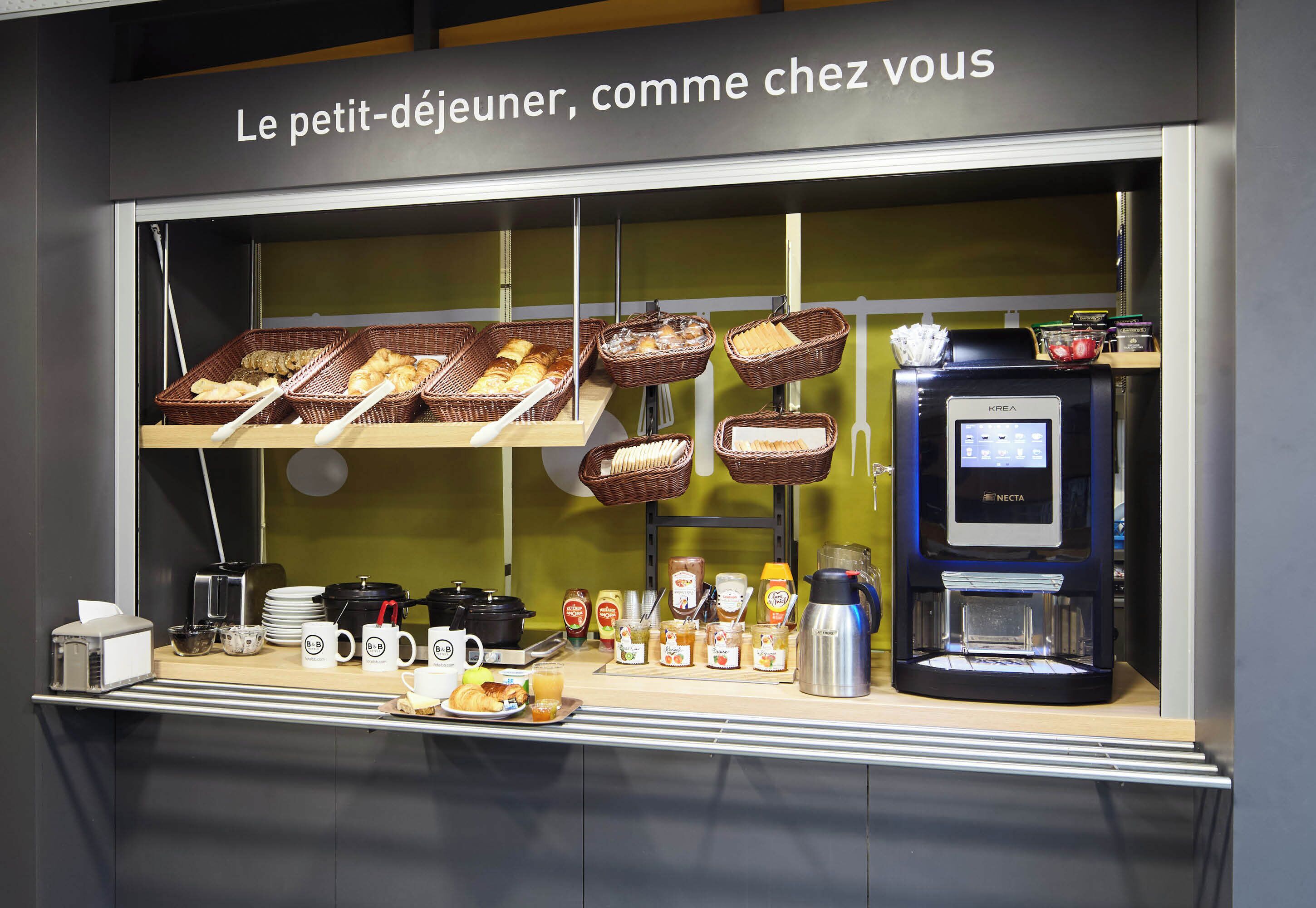 A breakfast buffet with baskets of bread, pastries, and a coffee machine.