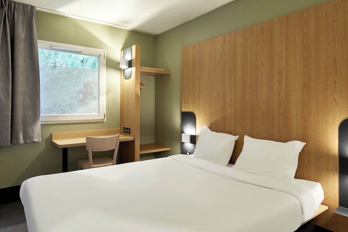 Una habitación de hotel con una cama, un escritorio y una silla.