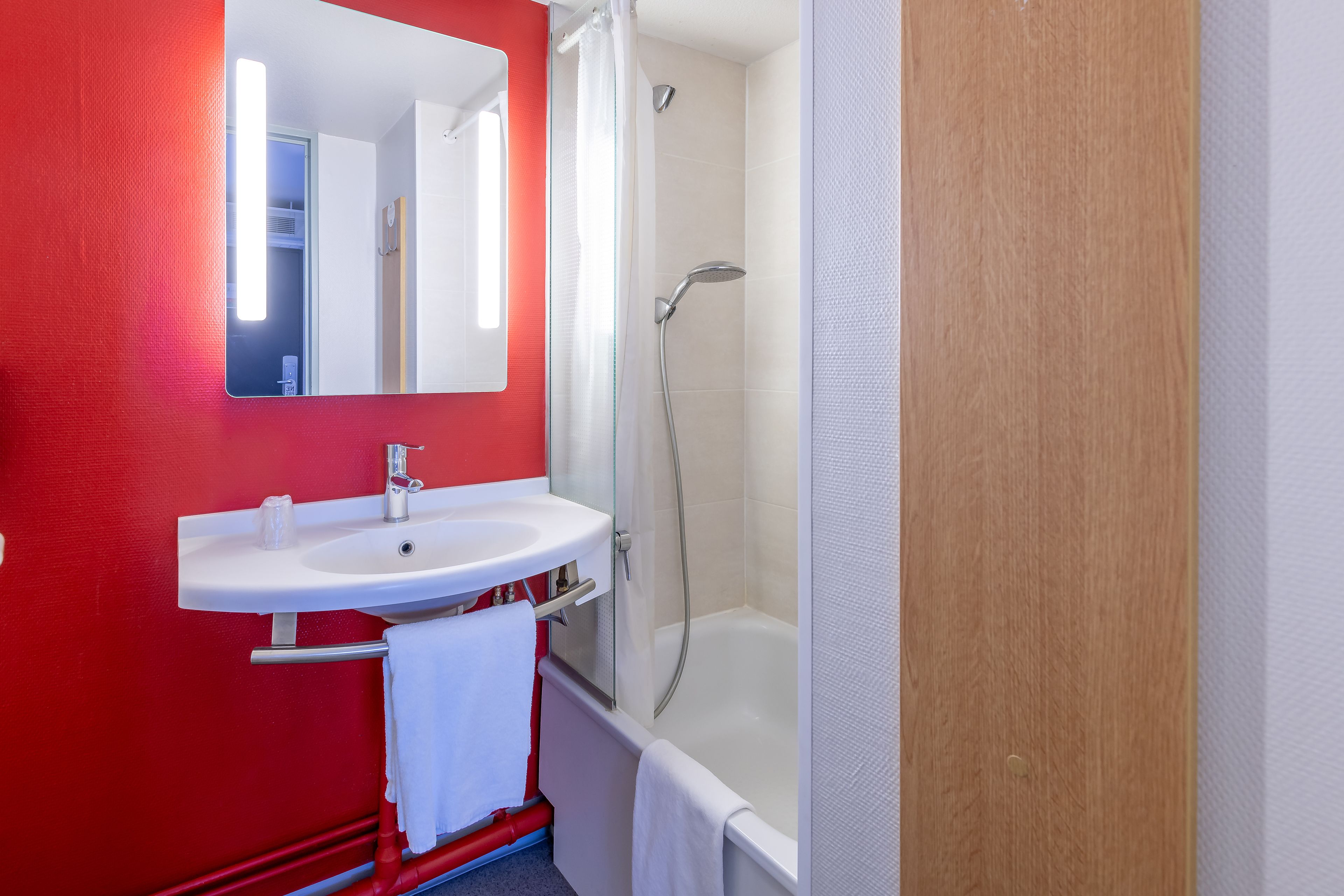 Un baño con lavamanos blanco, espejo y ducha.