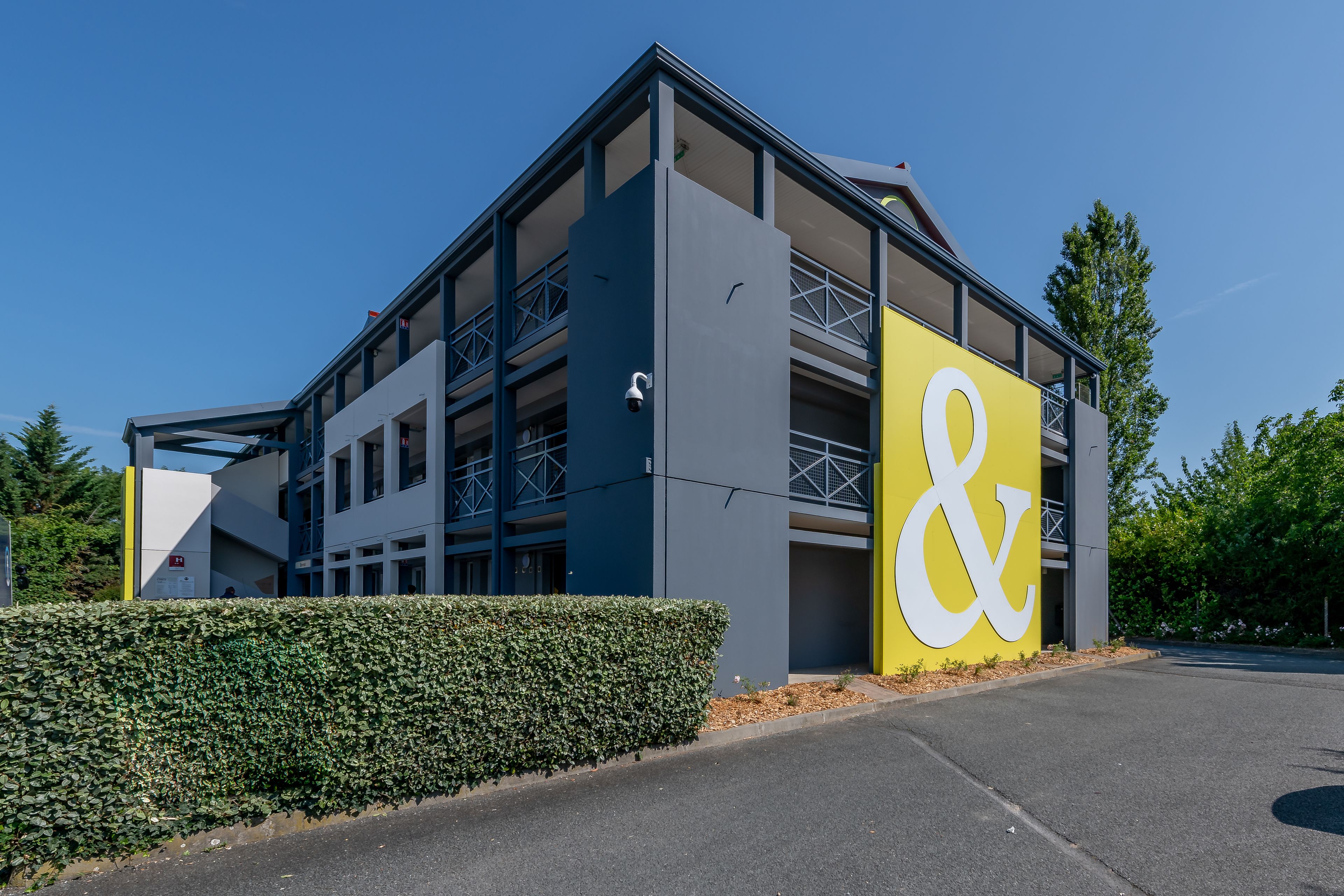 A modern building with a prominent yellow and white sign, multiple floors, and a covered outdoor area.