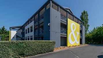 A modern building with a prominent yellow and white sign, multiple floors, and a covered outdoor area.