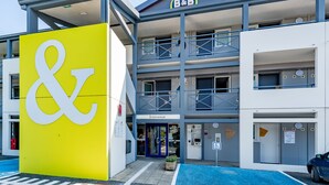 A B&B building with a large yellow sign, a blue entrance, and a wheelchair-accessible parking space. - B&B HOTEL Périgueux Boulazac (Boulazac-Isle-Manoire)