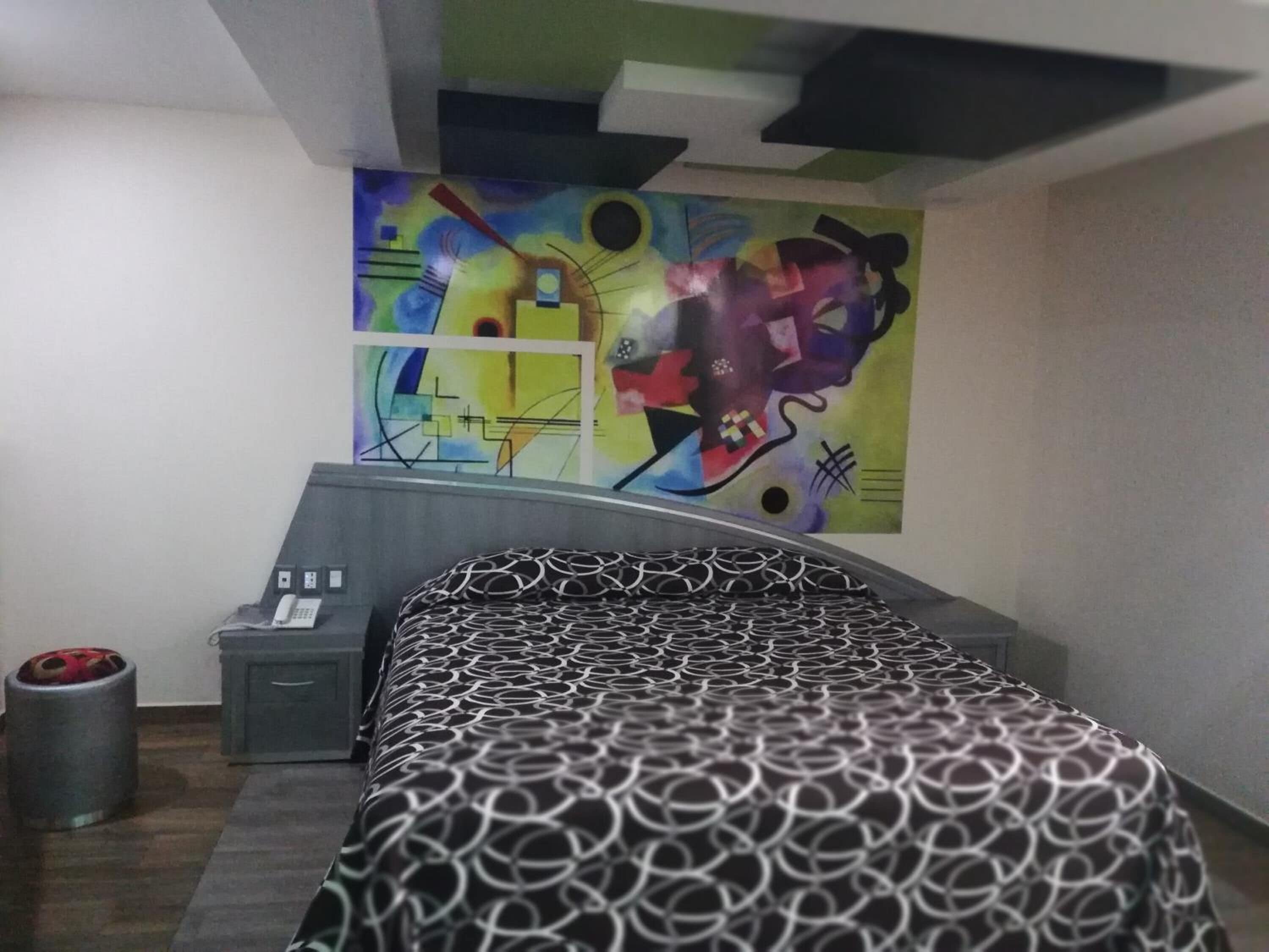 Un dormitorio con una cama, una mesita de noche, un teléfono y un cubo de basura.