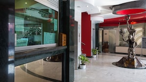 Un hall d’entrée moderne avec un comptoir d’accueil, une statue et un mur d’accent de couleur rouge.