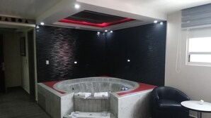 Une salle de bain moderne avec une baignoire sur pieds, un mur recouvert de carreaux noirs et blancs, un fauteuil en cuir noir et une petite table ronde.