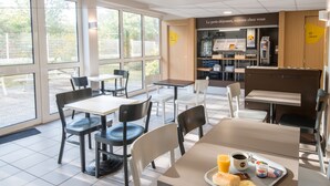 Une cafétéria moderne avec des tables et des chaises, un plateau contenant de la nourriture et des boissons, et un panneau en français.