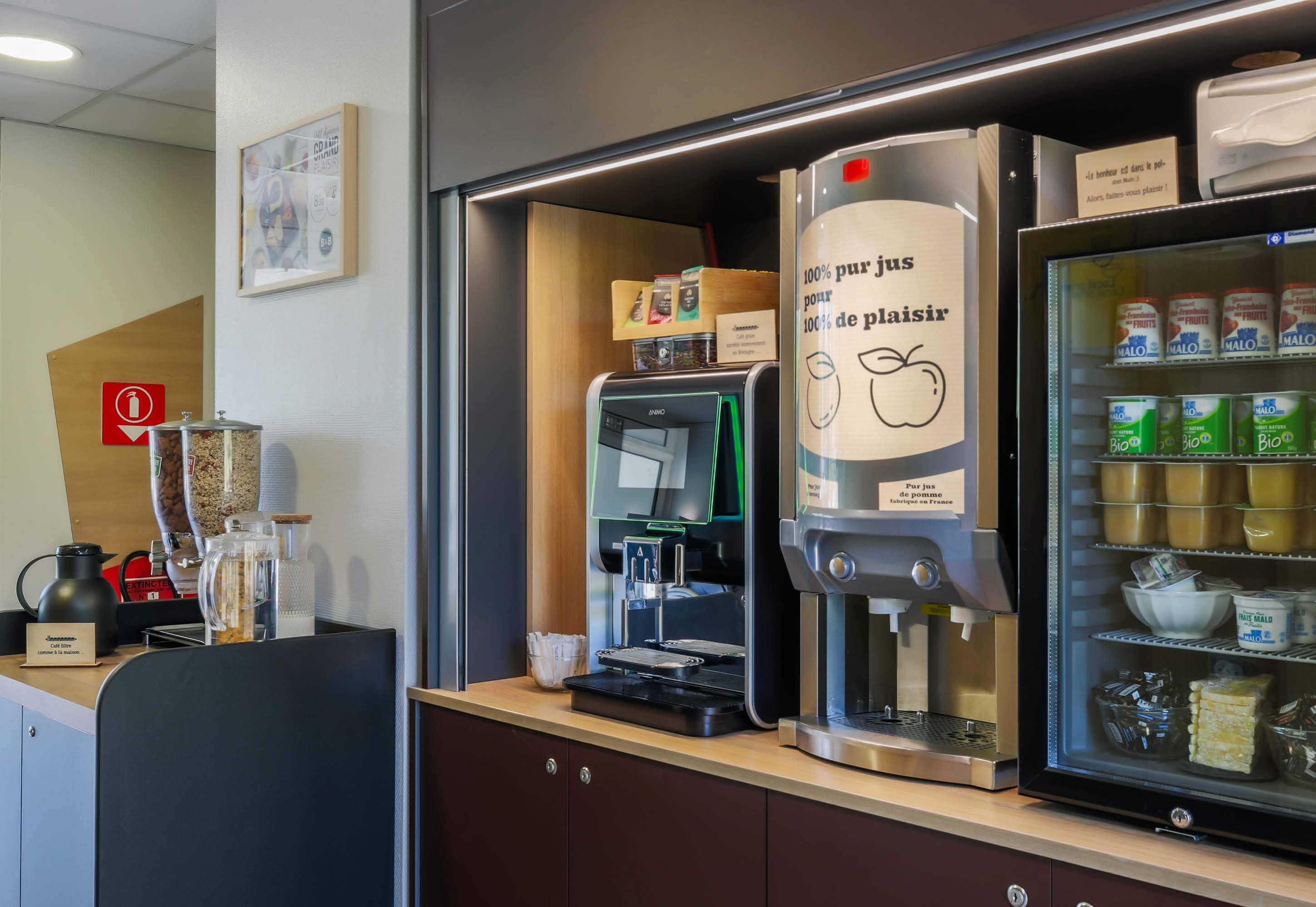 A coffee station with a coffee machine, a milk frother, and a refrigerated display with dairy products.