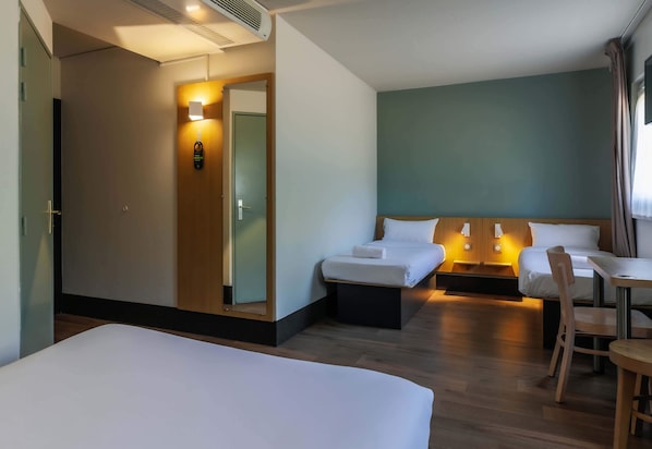 Habitación de hotel con dos camas, un escritorio y una silla.