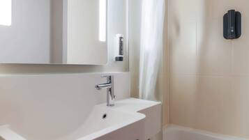 Une salle de bain moderne avec un lavabo blanc, un miroir et un distributeur de serviettes noir.