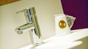 Un lavabo de salle de bain avec un robinet, une serviette et un sac en plastique orné du logo de l’hôtel.