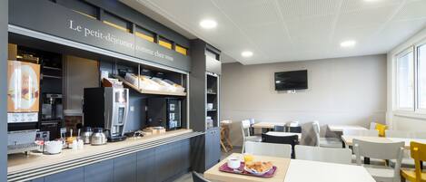 A modern cafe with a counter, seating area, and a television on the wall.
