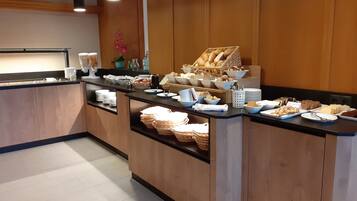 Um buffet de café da manhã com diversos alimentos e utensílios.