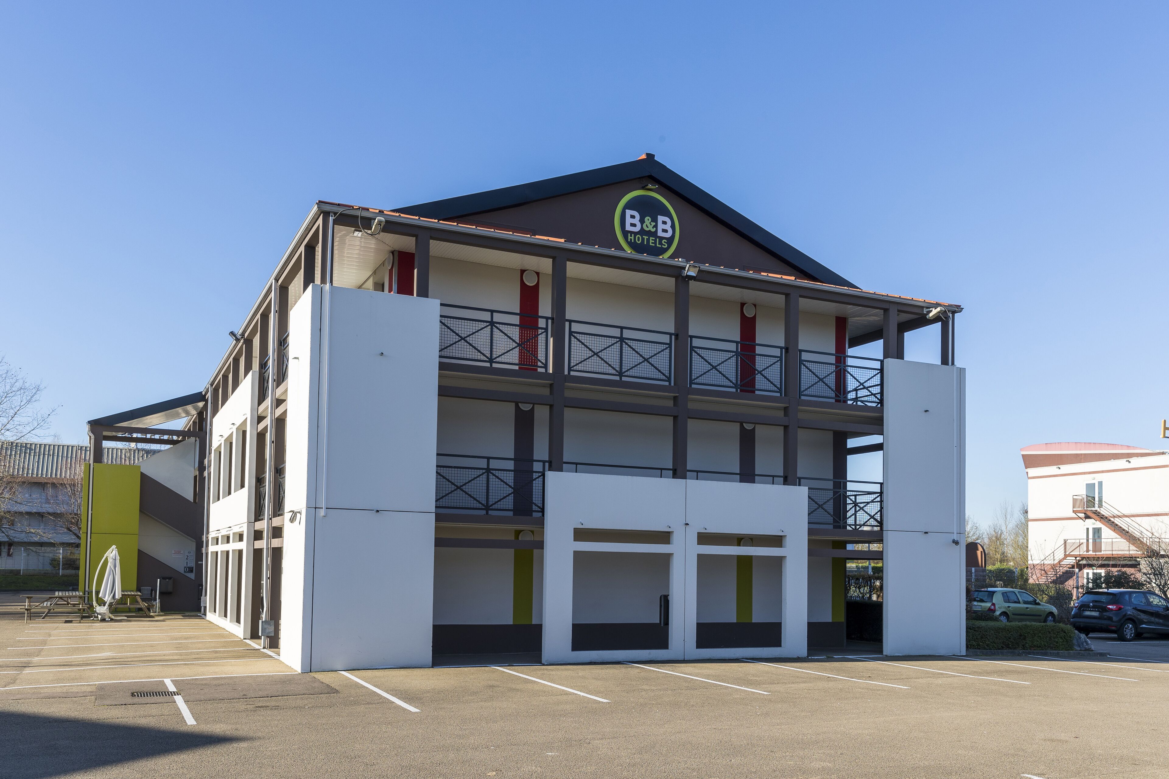 A B&B hotel with a two-story structure, a balcony on the upper floor, and a parking lot in front.