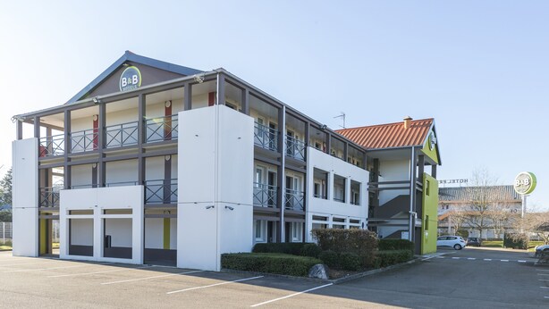 A B&B hotel with a two-story structure, a covered outdoor area, and a parking lot. - B&B HOTEL Auxerre Bourgogne (Moneteau)