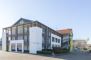 Un hotel B&B con una estructura de dos pisos, un espacio al aire libre techado y un estacionamiento.