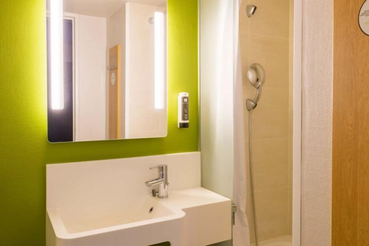 Une salle de bain avec un lavabo blanc, un miroir et une douche.