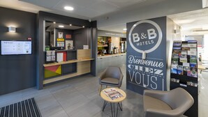 A B&B hotel reception area with a modern design, including a reception desk, seating area, and a display of brochures. - B&B HOTEL Auxerre Bourgogne (Moneteau)