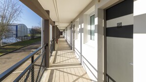 A corridor with a view of a building and a body of water. - B&B HOTEL Auxerre Bourgogne (Moneteau)