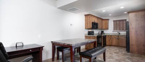 A kitchen with wooden cabinets, a dining table, and a bench.