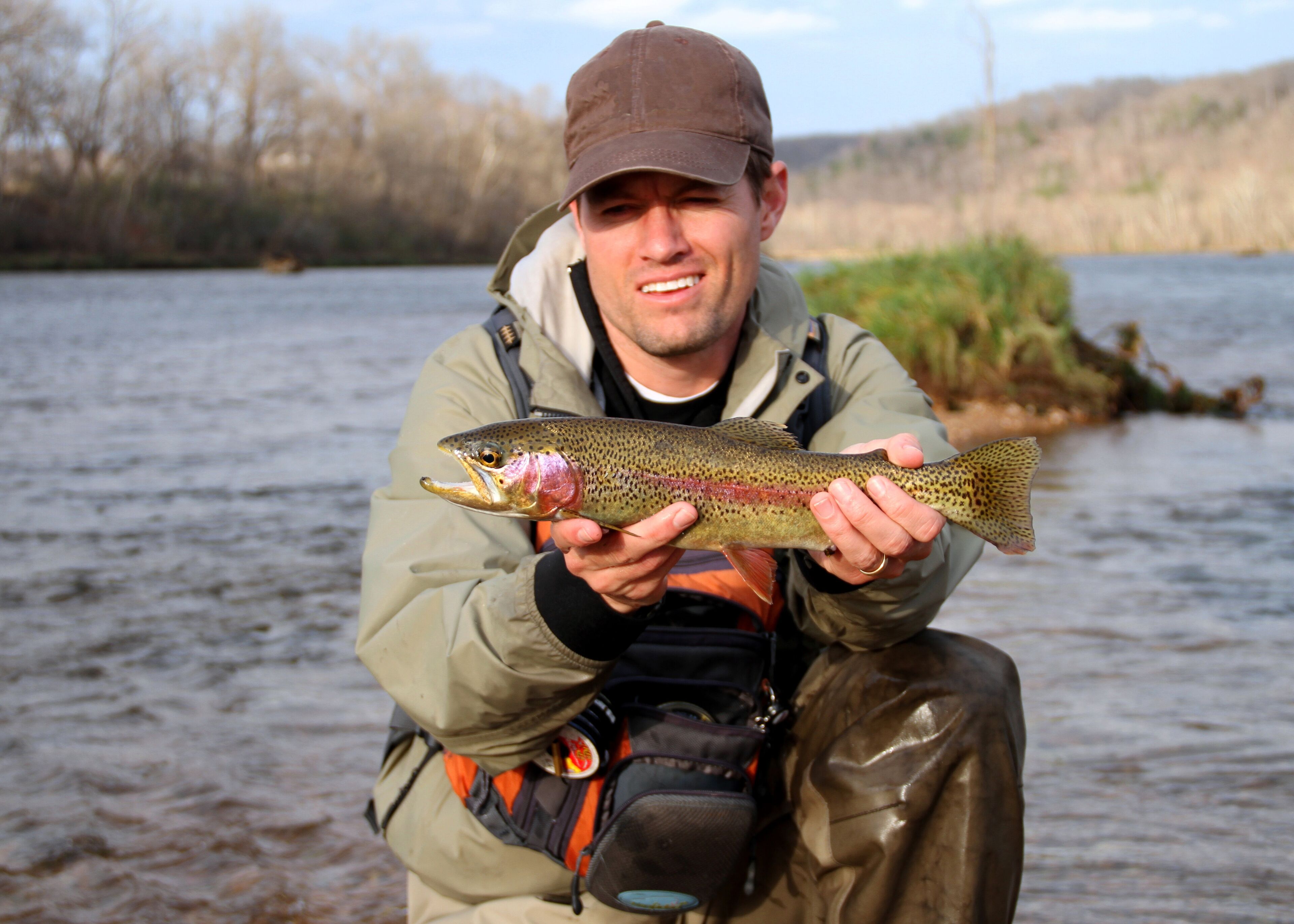 A person holding a fish by a river.