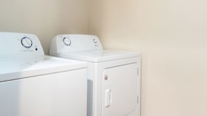 A laundry room with two white front-loading washing machines and a tiled floor. - Duchesne Suites (Duchesne)