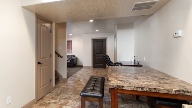 A spacious kitchen with a granite countertop and a bench. - Duchesne Suites (Duchesne)