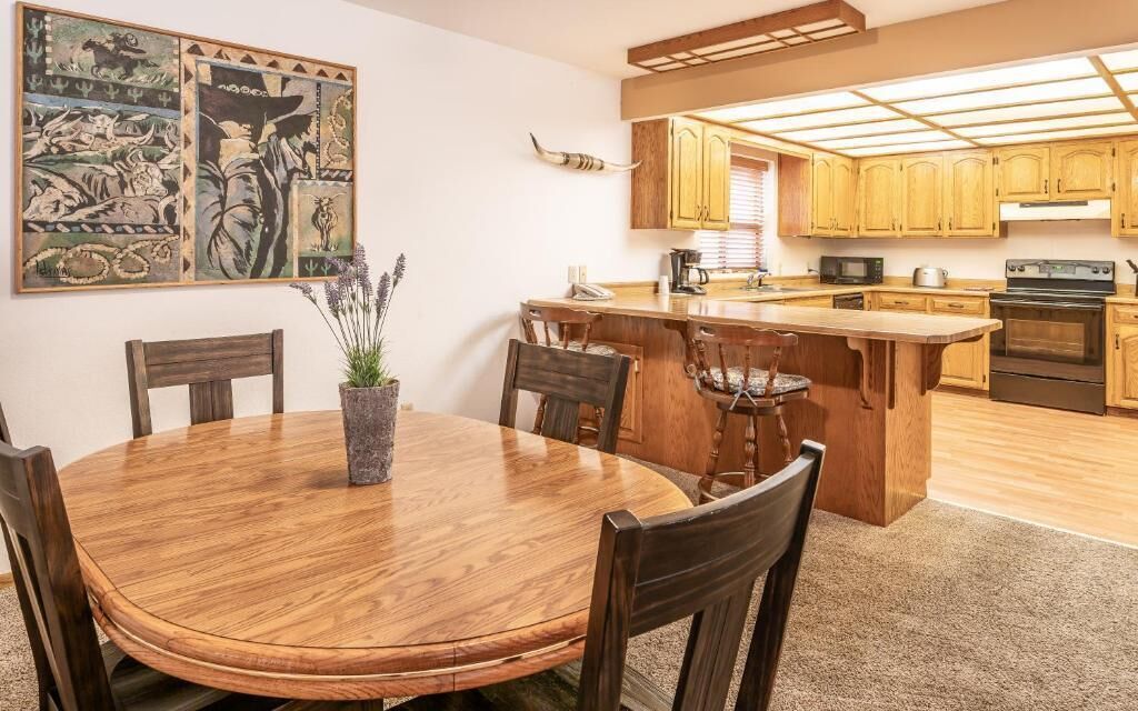 Una cocina con armarios de madera, una isla central y un comedor con una mesa redonda y sillas.