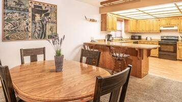Una cocina con armarios de madera, una isla central y un comedor con una mesa redonda y sillas.