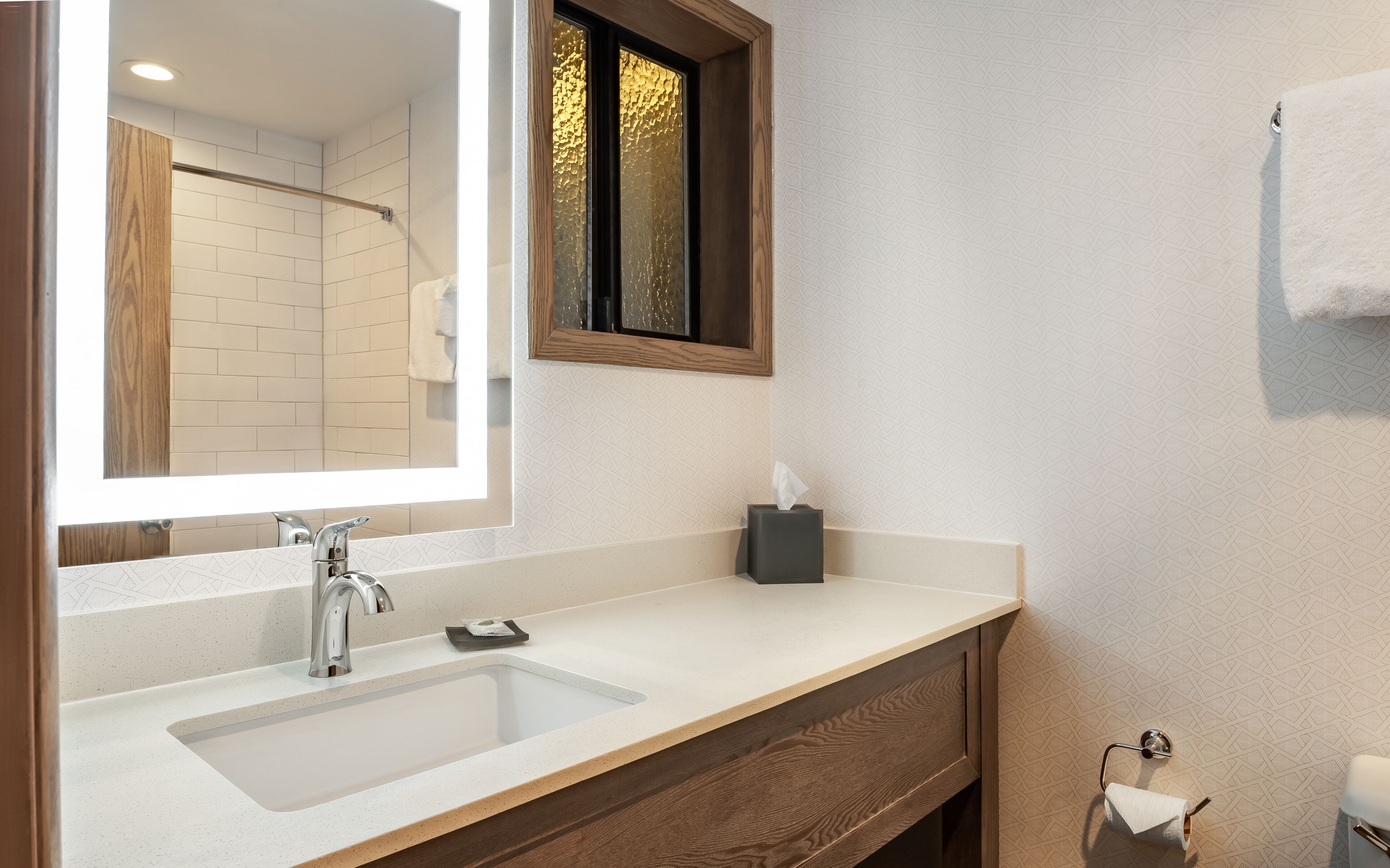 A bathroom with a white sink, a mirror, and a towel rack.