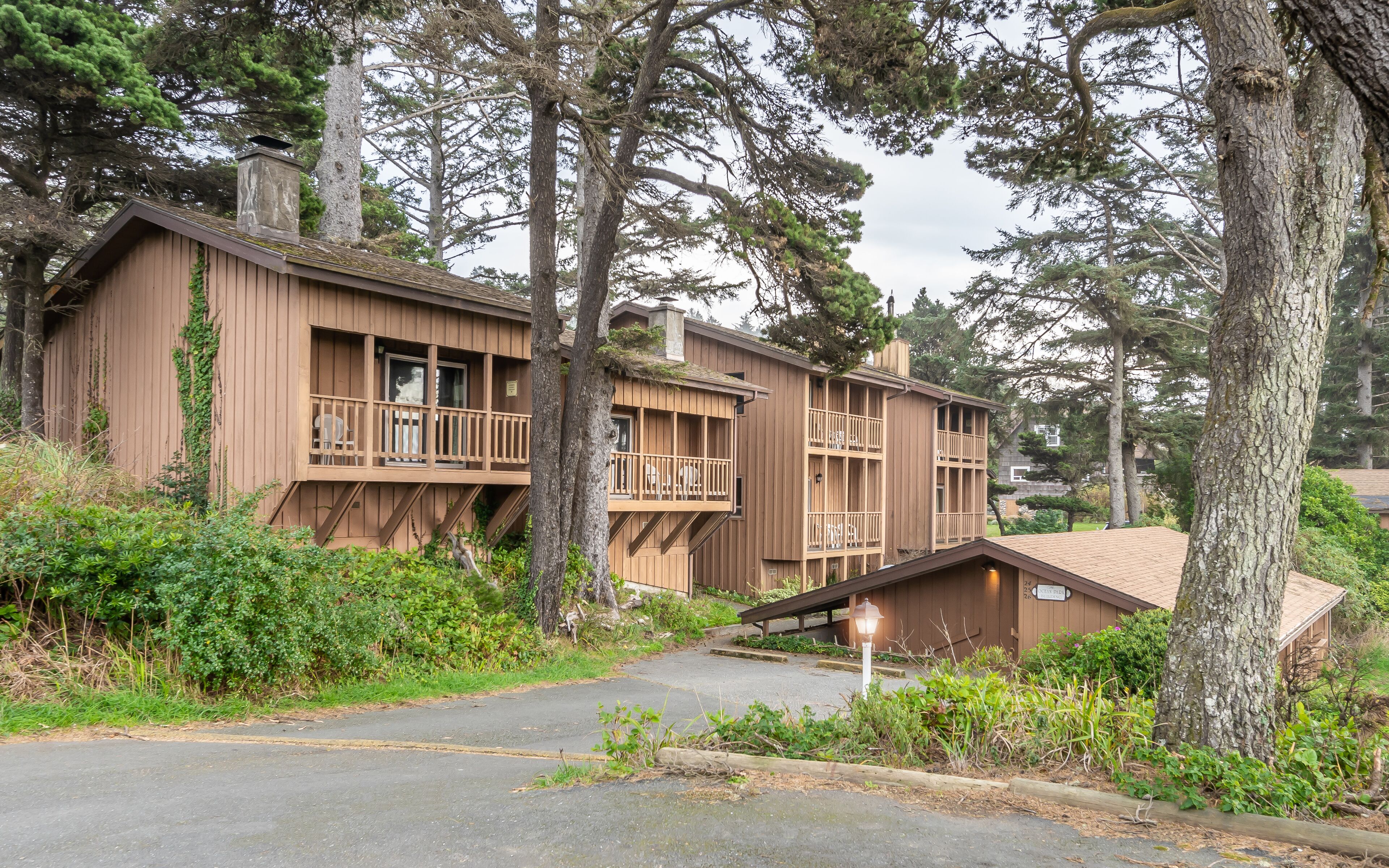 A wooden cabin-style building with multiple balconies, surrounded by dense forest.