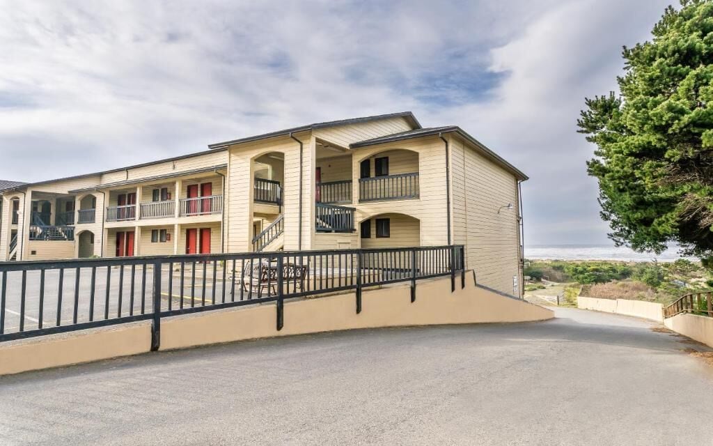 A multi-story motel with balconies, a central staircase, and a parking area.