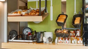 Un bufé de desayuno con diversos pasteles, pan y acompañamientos.
