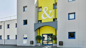 Un edificio con una fachada destacada de color amarillo y blanco, que presenta un gran símbolo de 'ampersand'.