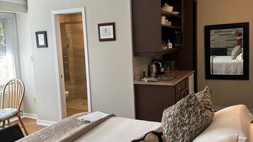 Habitación de hotel con cama, escritorio, silla, baño y una pequeña cocina.