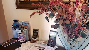 Un mostrador de recepción con folletos informativos, una señal enmarcada y un arreglo floral decorativo.