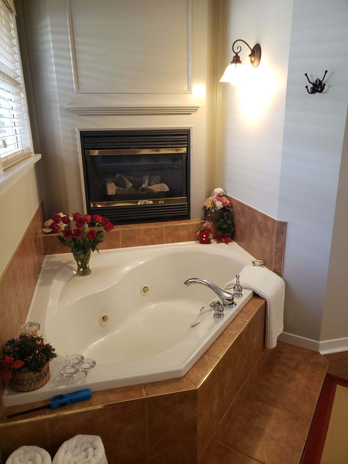 Ein Badezimmer mit einer großen Badewanne, einem Kamin, einer Wandleuchte und einem kleinen Weihnachtsbaum.