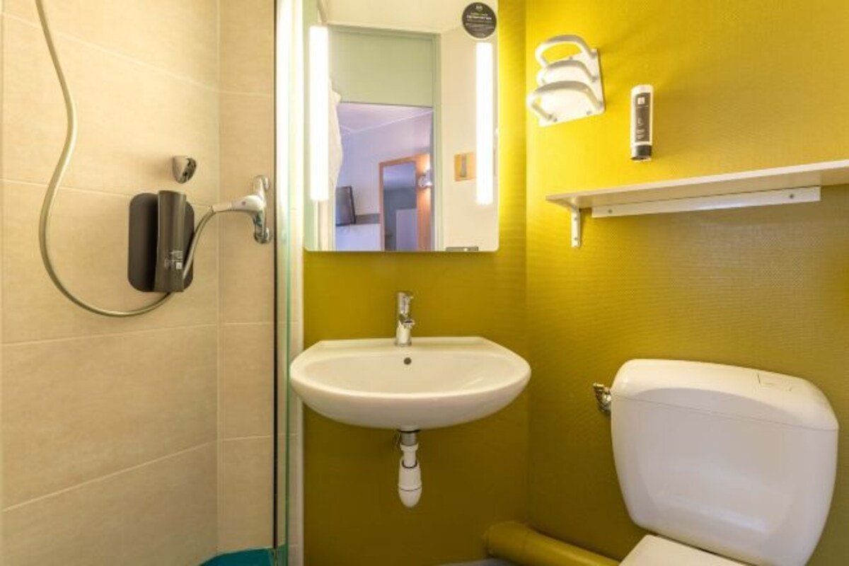 Un baño con lavamanos blanco, inodoro y zona de ducha.