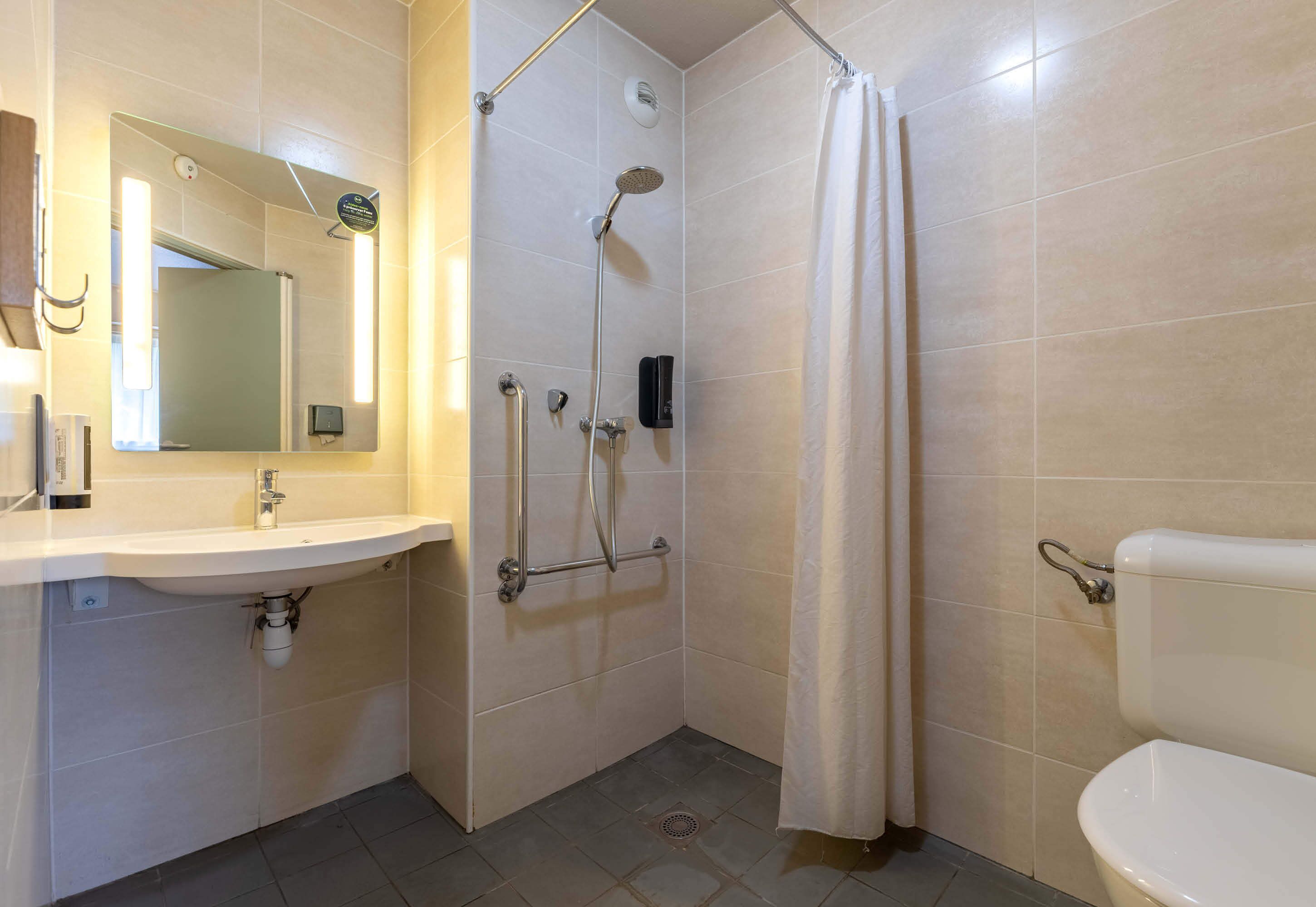 Een badkamer met een wastafel, spiegel, douche en toilet.