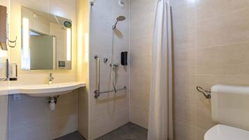 Een badkamer met een wastafel, spiegel, douche en toilet.