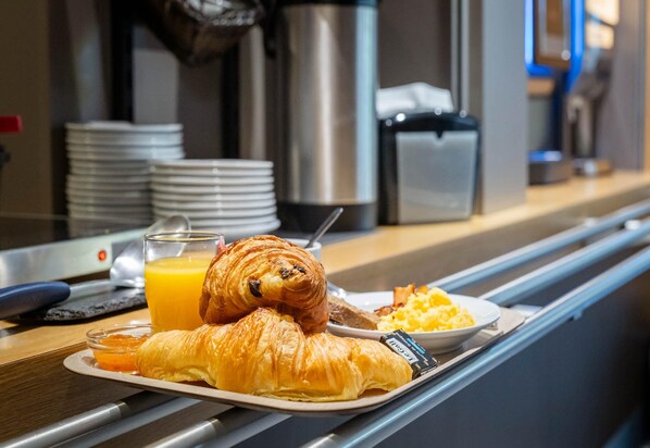 Breakfast items on a tray, including croissants, orange juice, and scrambled eggs. - B&B HOTEL Avignon (1) (Le Pontet)